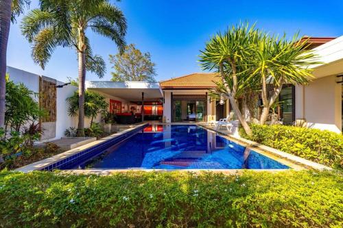 a swimming pool in front of a house with palm trees at 3 Bedroom Pool Villa in Great Location! BUB in Hua Hin