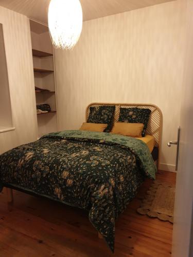 a bedroom with a bed and a chandelier at Logement meublé au calme in Vertrieu