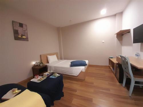 a hotel room with two beds and a desk and a table at Happy Home in Nha Trang