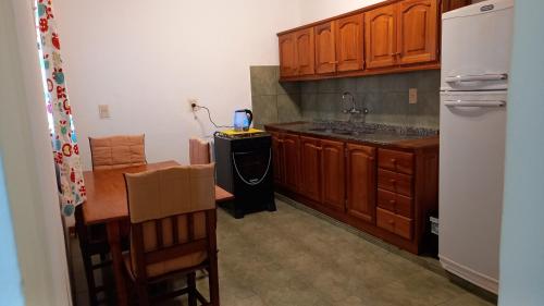 a kitchen with wooden cabinets and a table and a refrigerator at Apartment El sueño de Julieta in Puerto Iguazú