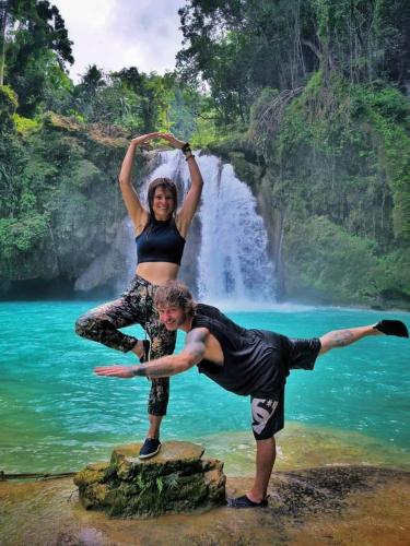 a man and woman standing on a rock in front of a waterfall at House of TamSe Laagans ' Inn in Badian