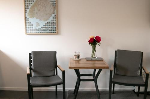 瓦納卡的住宿－Wanaka Lake Studio (New)，两把椅子和一张带花瓶的桌子