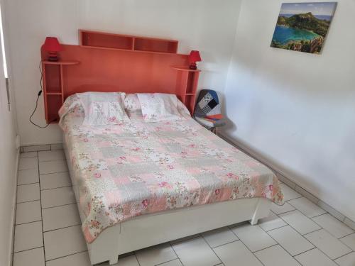 Dormitorio pequeño con cama con cabecero rojo en Accueil Créole en Sainte-Rose