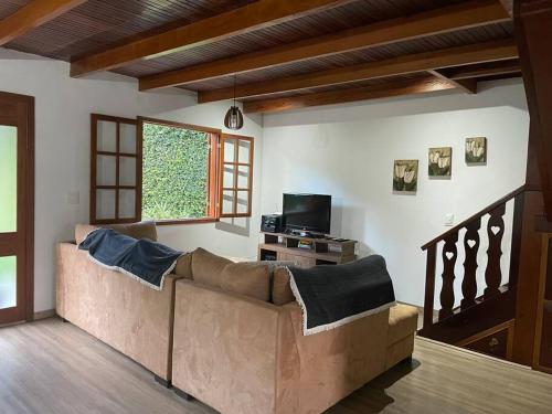 ein Wohnzimmer mit einem Sofa und einem TV in der Unterkunft Confortável Chalet na Serra proximo ao Centro in Nova Friburgo