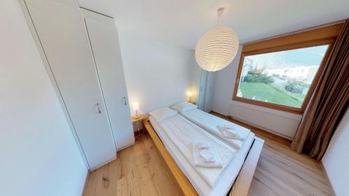 - une chambre avec un lit et une grande fenêtre dans l'établissement Apartment Piz Cotschen, à Pontresina