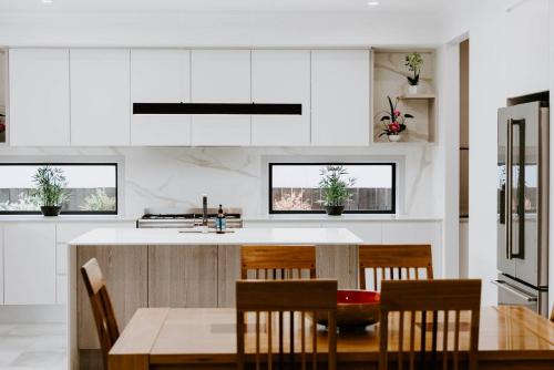 a kitchen with white cabinets and a table and chairs at The Top Spot - A Modern All-Season Retreat in Mudgee