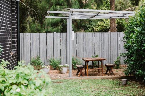 a pergola with a table and benches in a garden at The Top Spot - A Modern All-Season Retreat in Mudgee