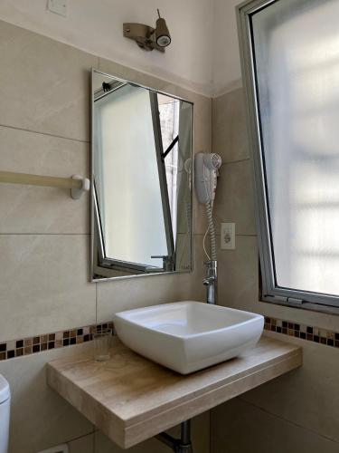 a white sink in a bathroom with a mirror at Hotel Lobato in Paysandú