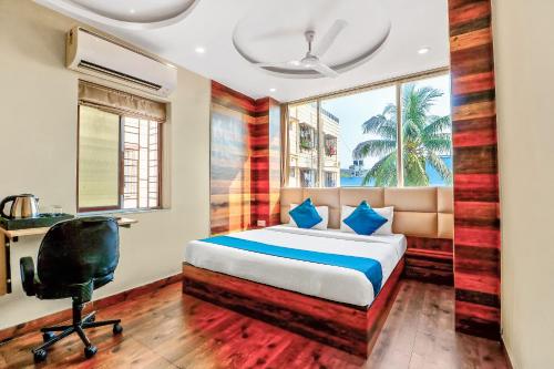 a bedroom with a bed and a desk and a chair at Super Hotel O Park Circus Near Birla Mandir in Kolkata