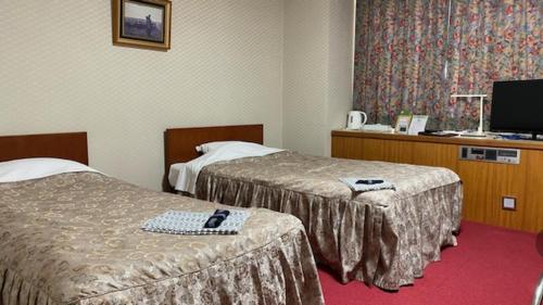 a hotel room with two beds and a television at Hotel Portside Imabari in Imabari