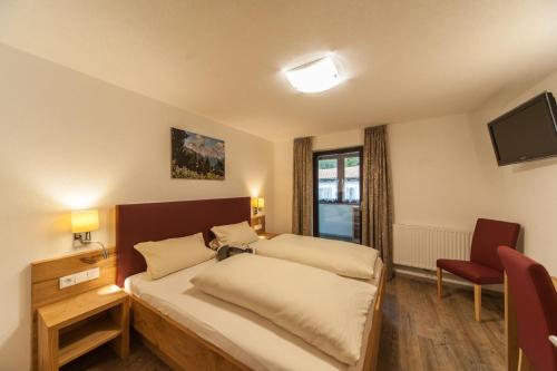 a bedroom with two beds and a tv and a chair at Appartements Wacker in Bichlbach