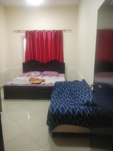ein Schlafzimmer mit 2 Betten und einem roten Vorhang in der Unterkunft Furnished Apartment in Dubai