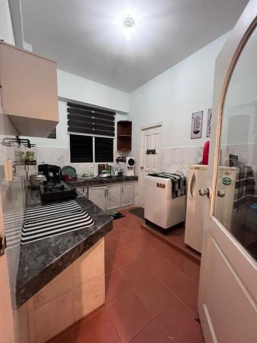 cocina con electrodomésticos blancos y suelo de baldosa roja en RUMAH SINGGAH APARTMENT en Kuah