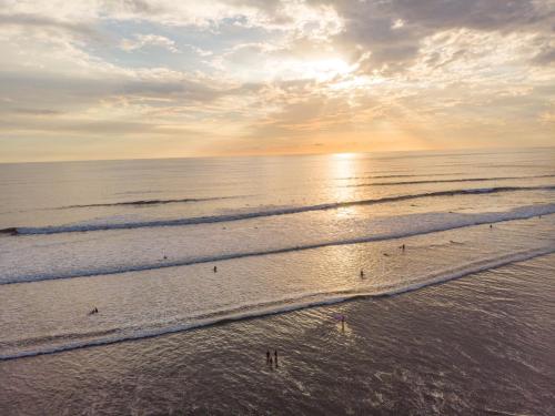 a beach with people walking in the water at Shark Town Mal Pais in Santa Teresa Beach