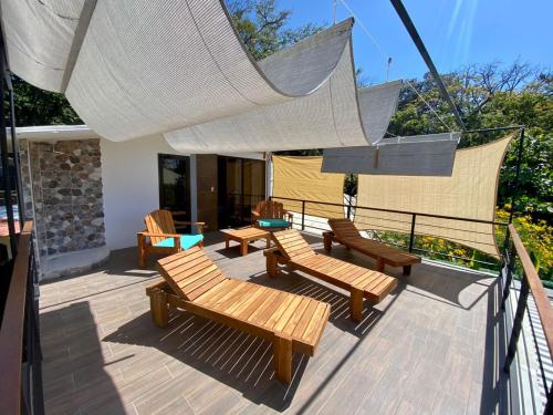 a deck with chairs and tables and a net at Shark Town Mal Pais in Santa Teresa Beach