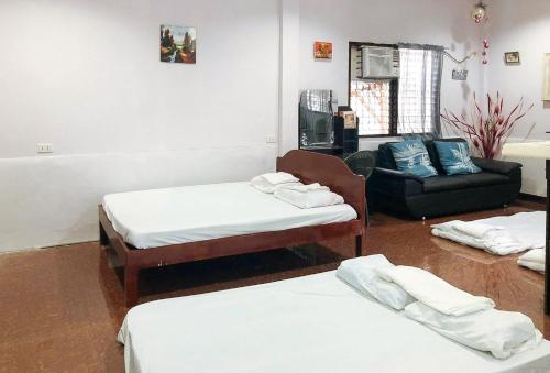 a room with two beds and a chair and a couch at Irah's Guest House RedPartner in Banhigan