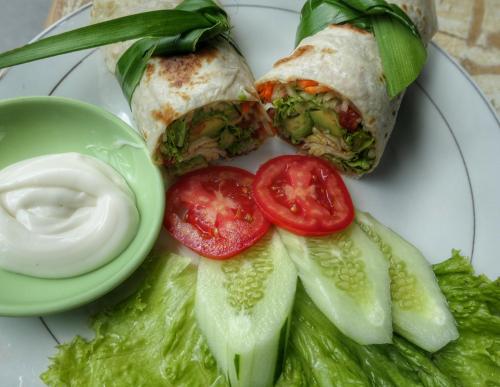 a plate with a sandwich and tomatoes and lettuce at Sumatra Orangutan Discovery Villa in Bukit Lawang