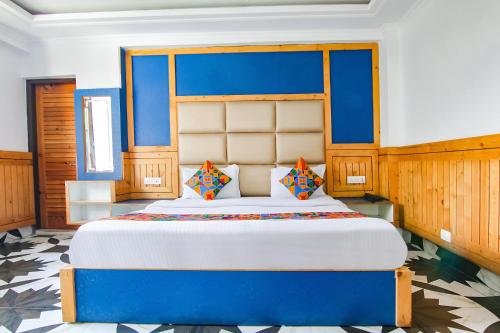 a bedroom with a large bed with a blue headboard at FabHotel Rosewood Inn I in Dharamshala