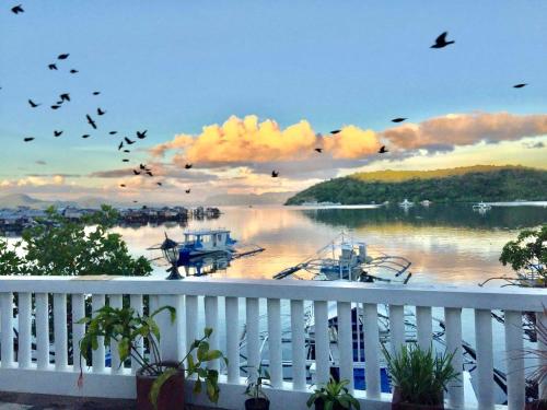 a flock of birds flying over a river with boats at Casa Osmena, Culion in Culion