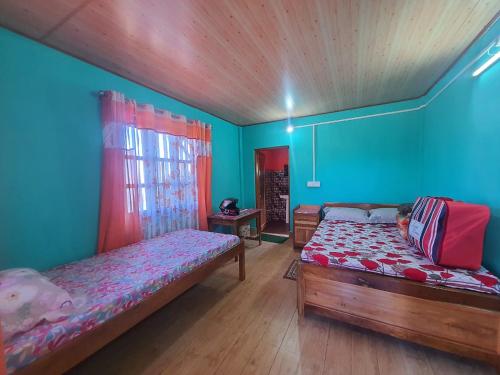- une chambre avec 2 lits et des murs bleus dans l'établissement Chewa Homestay, à Mangpu