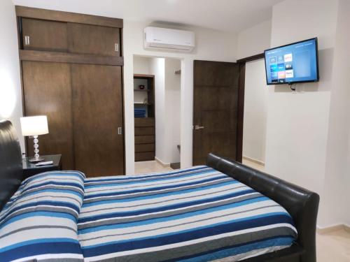 een slaapkamer met een bed en een flatscreen-tv bij Brujas Tower Beach Resort in Mazatlán