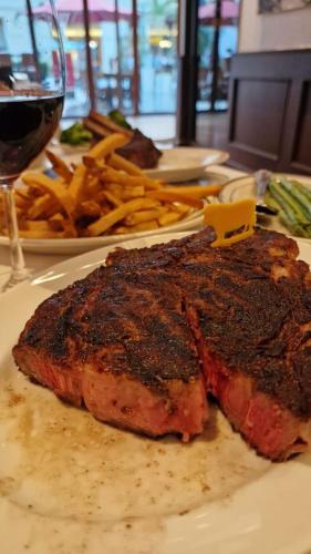 a piece of meat on a plate with fries and a glass of wine at Tablas Seaview Homestay in Ferrol