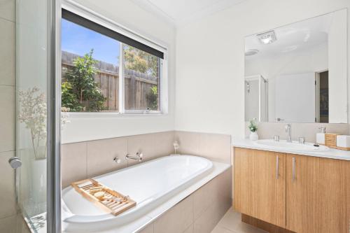 a bathroom with a tub and a sink and a window at Aerial Beach House 2 in Torquay