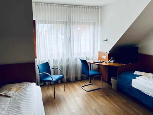 a hotel room with a bed and a desk with two chairs at Hotel & Restaurant Goldener Pflug in Ludwigsburg