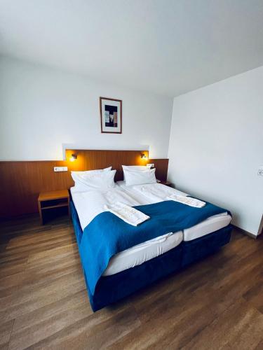 a bedroom with a large bed with a blue blanket at Hotel & Restaurant Goldener Pflug in Ludwigsburg