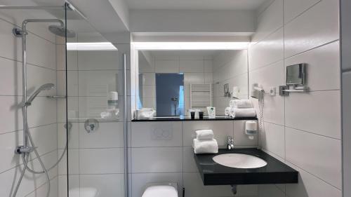 a white bathroom with a sink and a shower at Hotel & Restaurant Goldener Pflug in Ludwigsburg