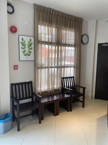 ein Esszimmer mit 2 Stühlen, einem Tisch und einem Fenster in der Unterkunft D'Green Hotel Kuching in Kuching