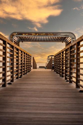 a wooden boardwalk leading to the ocean under a cloudy sky at voco Dubai Monaco, the Heart of Europe by IHG in Dubai