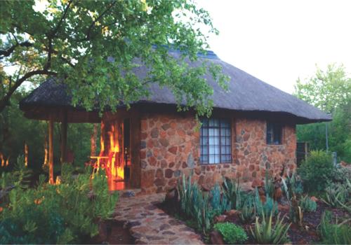 a small stone house with a thatched roof at Waterside Cottages & Villas - Self Catering in Gaborone