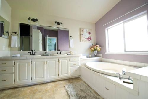 a white bathroom with a tub and a large window at Spacious Peaceful Country Home 1 Mile from Town 