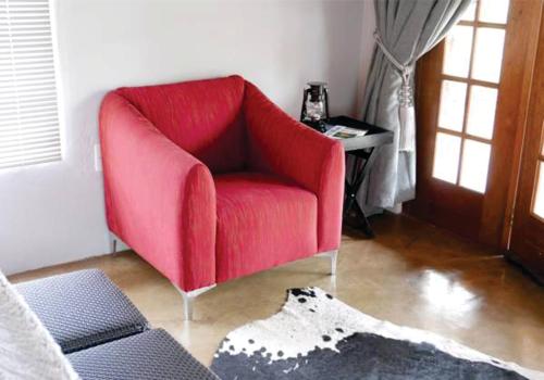 a red chair in a living room with a table at Waterside Cottages in Gaborone