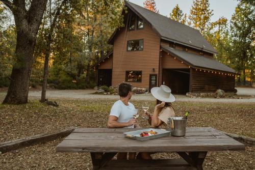 a man and woman sitting at a picnic table in front of a barn at Lovers nest by Casa Oso with private hiking trails and pond in Mariposa