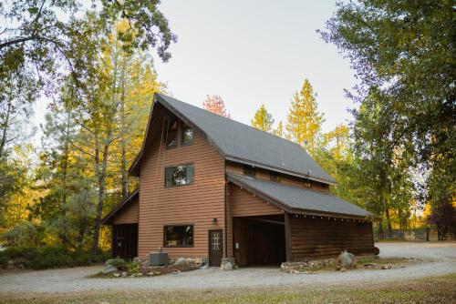 a large wooden barn with a black roof at Lovers nest by Casa Oso with private hiking trails and pond in Mariposa
