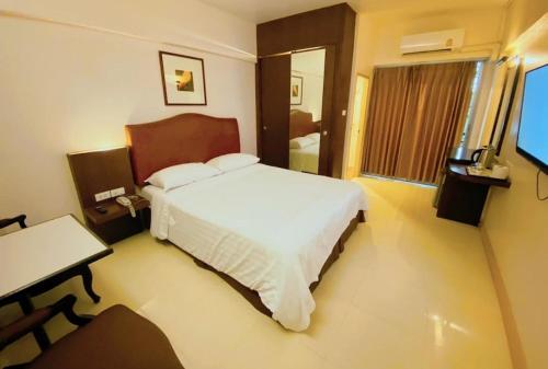 een slaapkamer met een bed, een bureau en een televisie bij Synsiri Ladprao 130 in Ban Bang Toei (1)