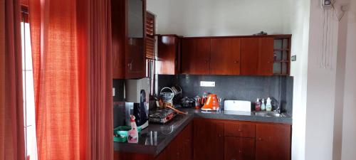 cocina con armarios de madera y encimera en HIRU VILLA, en Athurugiriya