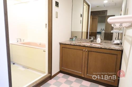 a bathroom with a sink and a tub and a mirror at NK BLD6F Sapporo 3LDK 3BR 1 floor 1 room in Sapporo