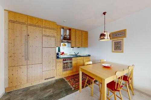 cocina con armarios de madera y mesa de madera en Apartment Sur Puoz 2A en Samedan