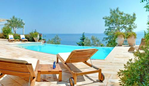 a couple of chairs sitting next to a swimming pool at Corfu Luxury Villas in Barbati
