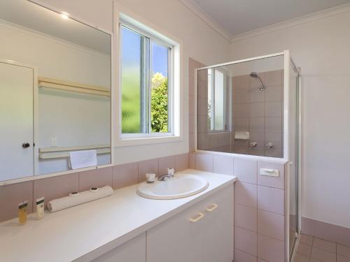 a white bathroom with a sink and a mirror at 23 Hilton in Tewantin