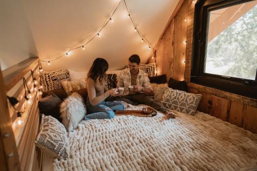 a man and woman sitting on a bed with a dog at Lovers nest by Casa Oso with private hiking trails and pond in Mariposa