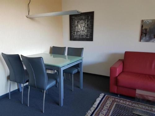 um quarto com uma mesa e cadeiras e um sofá vermelho em Gemütliche Ferienwohnung im Disentiserhof mit Traumblick übers Rheintal em Disentis