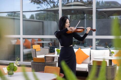 a woman playing a violin in a restaurant at Home2 Suites by Hilton Guiyang Nanming Jiyuan in Guiyang