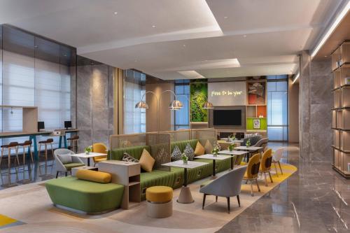 a lobby of a hotel with tables and chairs at Home2 Suites by Hilton Guiyang Airport in Guiyang