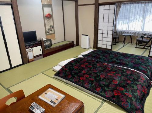 a room with a large bed with flowers on it at Ryokan Murayama in Takayama