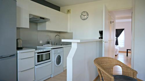 une cuisine avec des armoires blanches et une laveuse et une sécheuse dans l'établissement Little Suite - Jean, à Lille