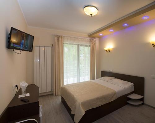 a bedroom with a bed and a tv on the wall at Hotel Holiday Maria in Băile Herculane